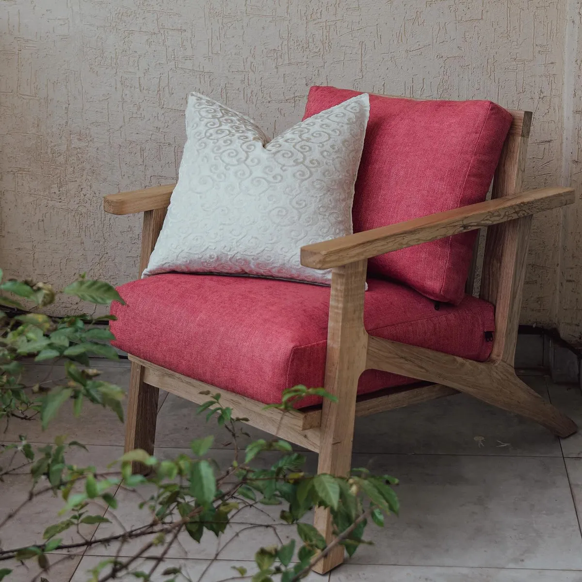 Oak lounge chair with raspberry cushions on a terrace
