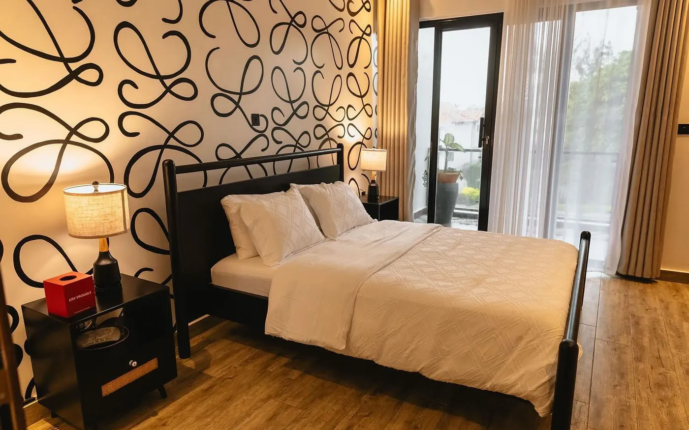 Black wooden bed and bedside tables in front of a patterned feature wall