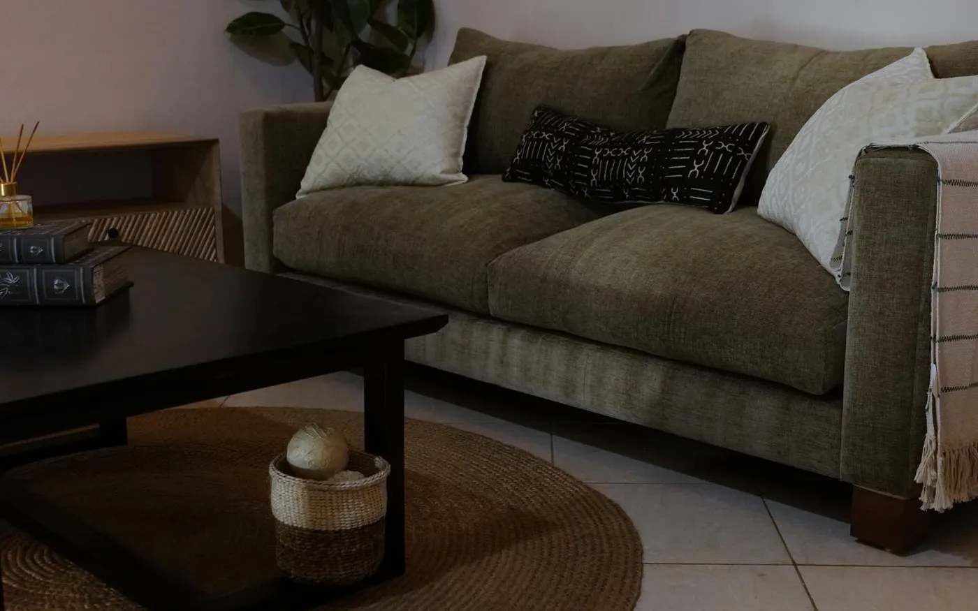 Olive sofa with patterned cushions beside a black coffee table
