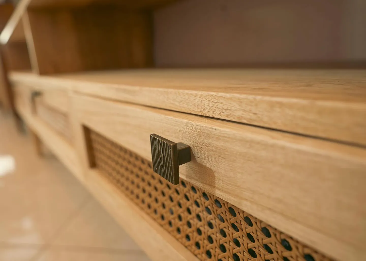 Close-up of a cane drawer front and textured brass pull