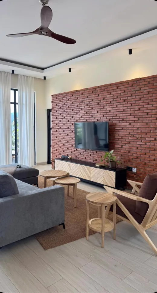 Living room with a brick wall, herringbone media unit, nesting tables and a lounge chair