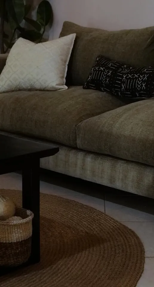 Olive sofa with patterned cushions beside a black coffee table