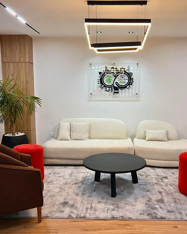Office reception with curved sofas, red stools and wood-clad columns