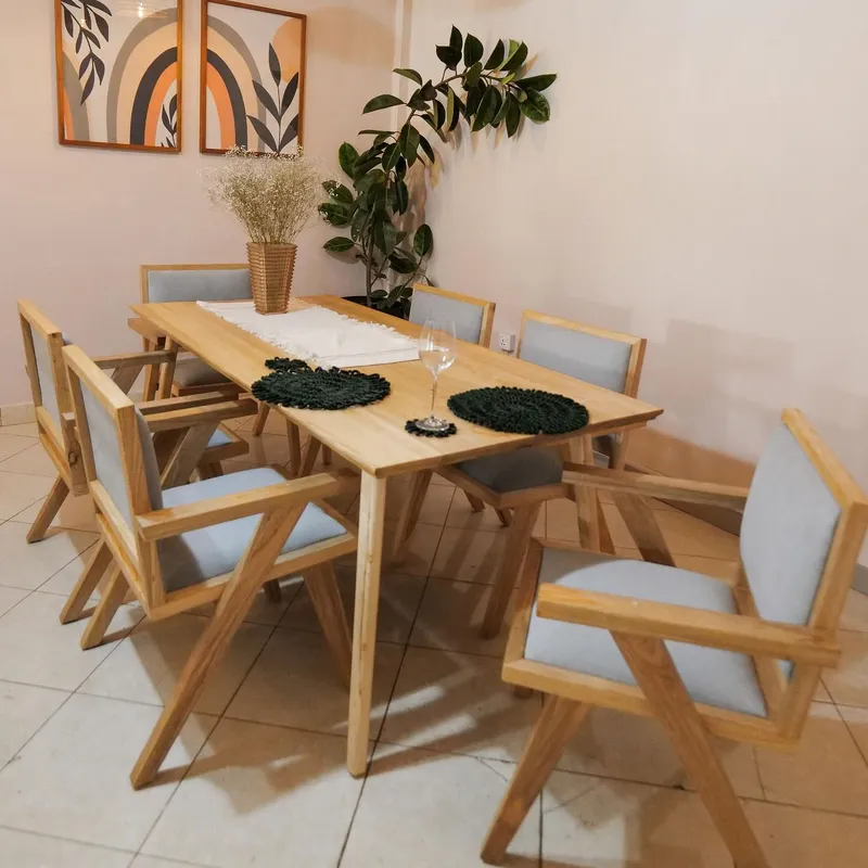 Light oak dining table and armchairs under woven pendants