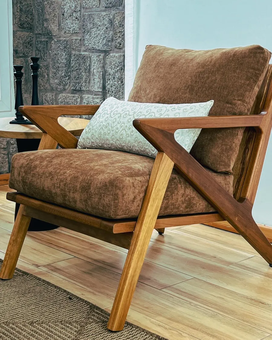 Teak lounge chair with brown cushions against a stone wall