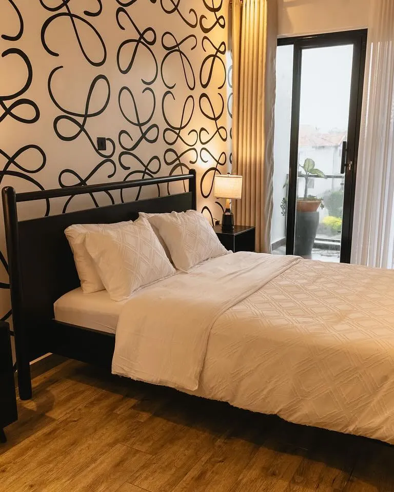 Black wooden bed and bedside tables in front of a patterned feature wall