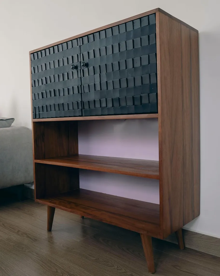 Teak cabinet with carved black block doors above open shelves