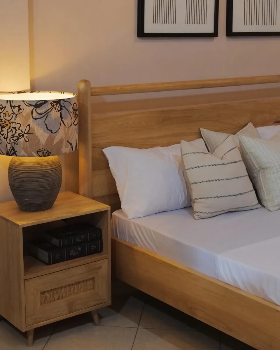 Oak bed and bedside table with a cane drawer under a lit lamp