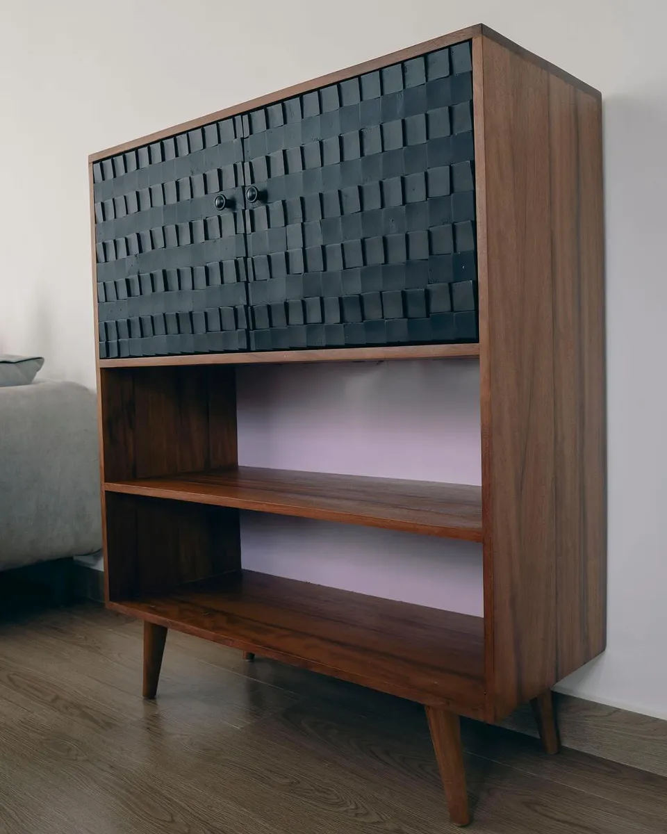 Teak cabinet with carved black block doors above open shelves