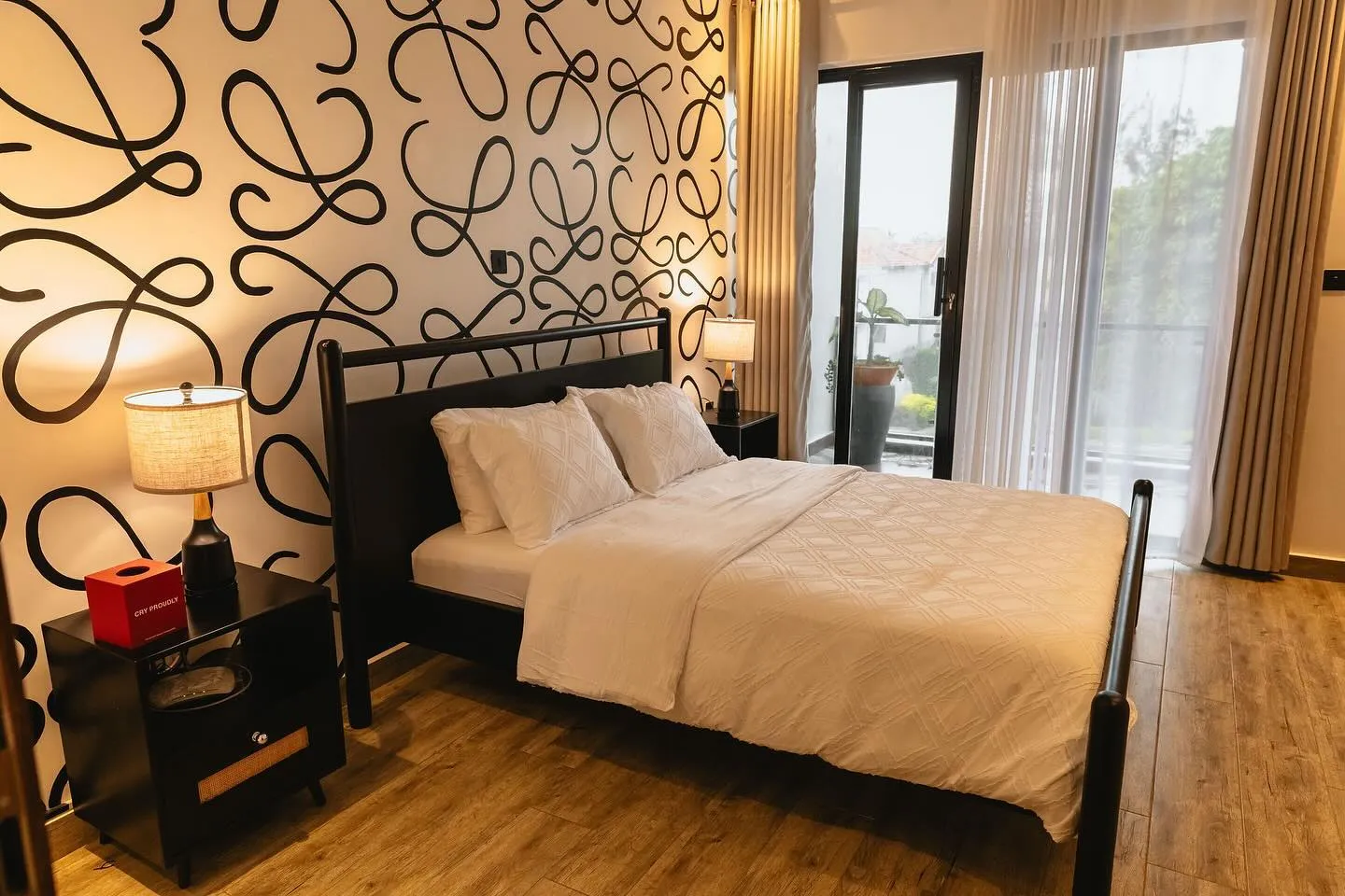 Black wooden bed and bedside tables in front of a patterned feature wall