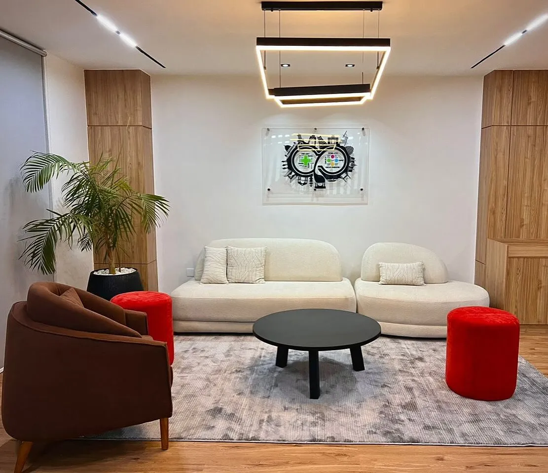 Office reception with curved sofas, red stools and wood-clad columns