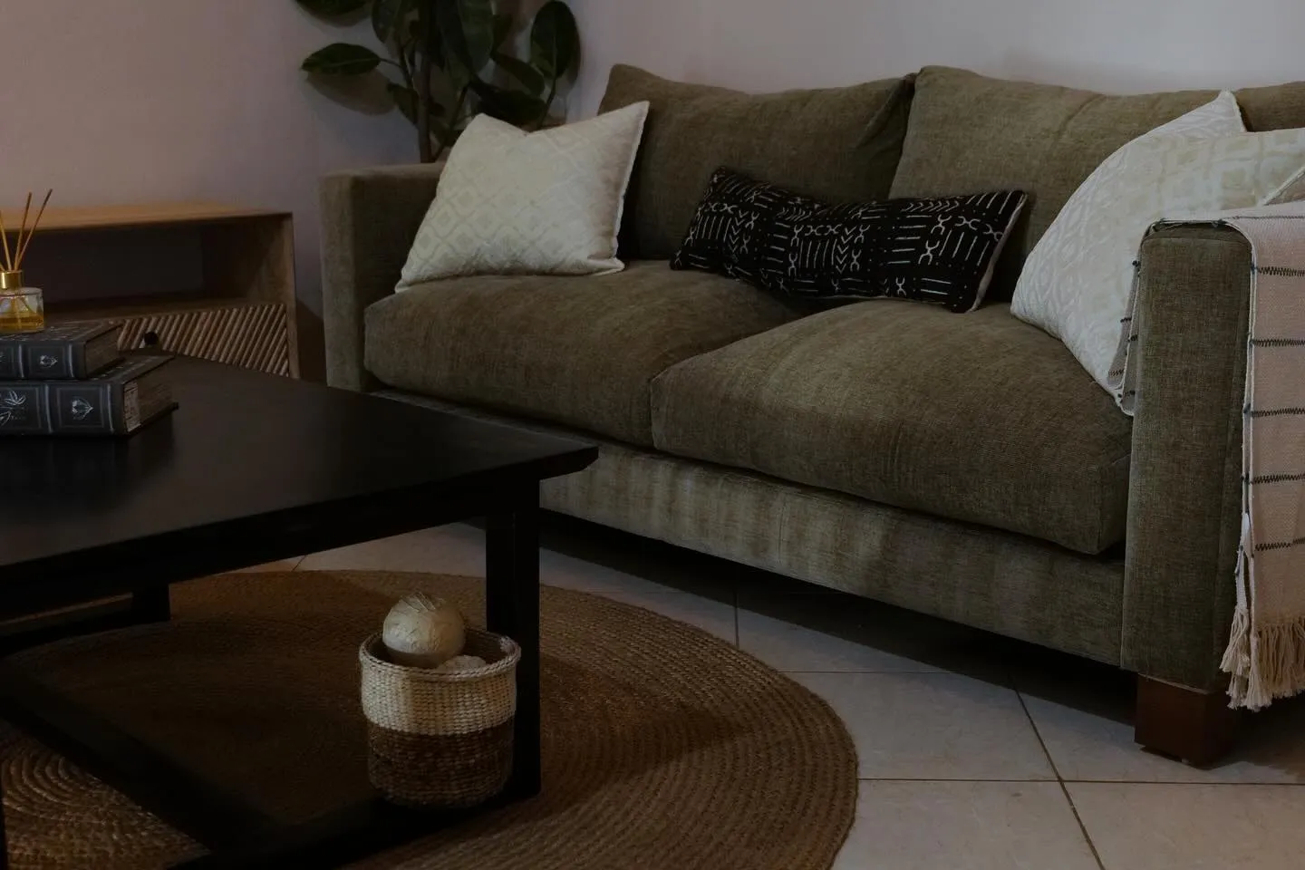Olive sofa with patterned cushions beside a black coffee table