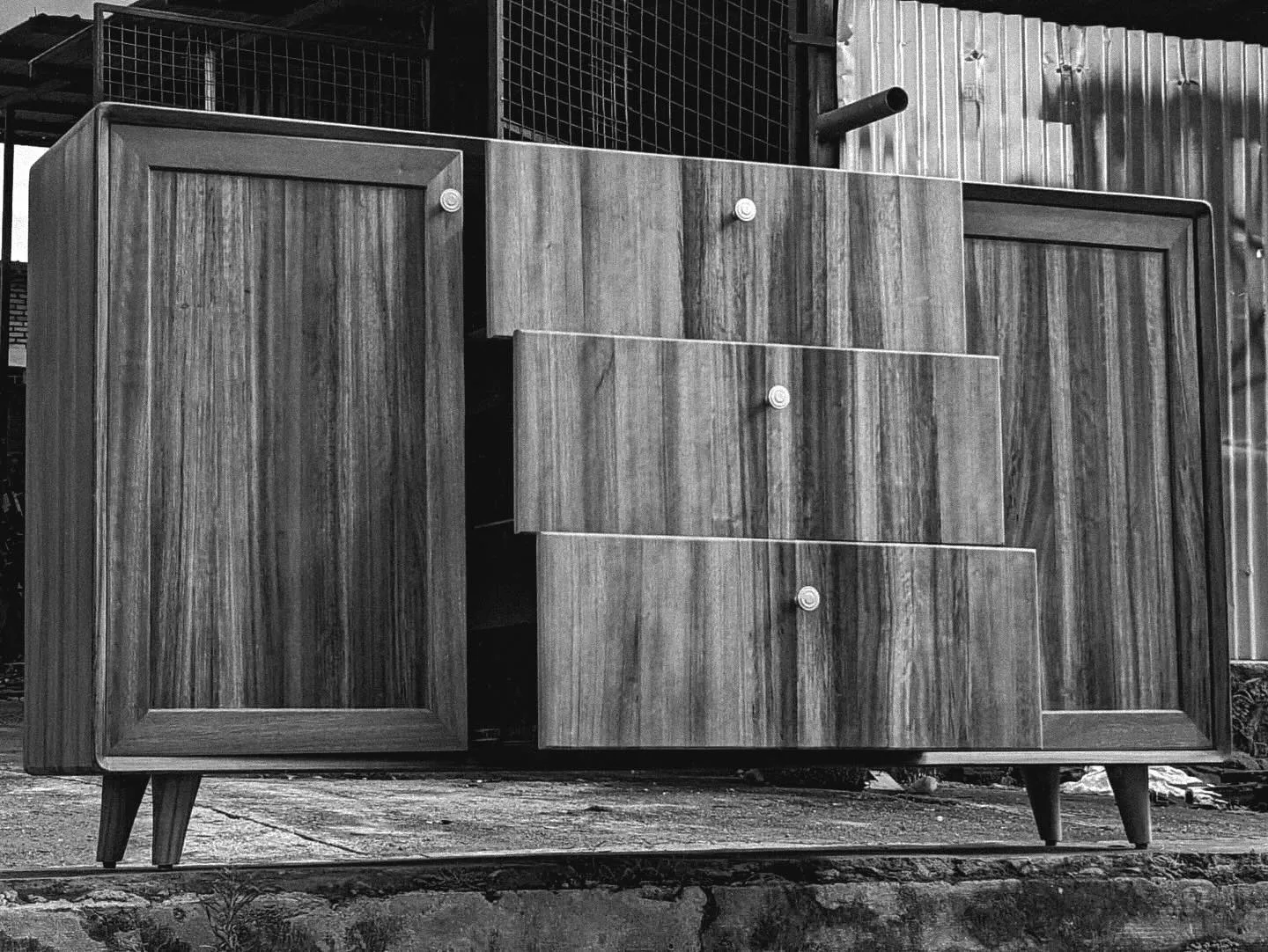 A finished sideboard in the workshop yard, in black and white